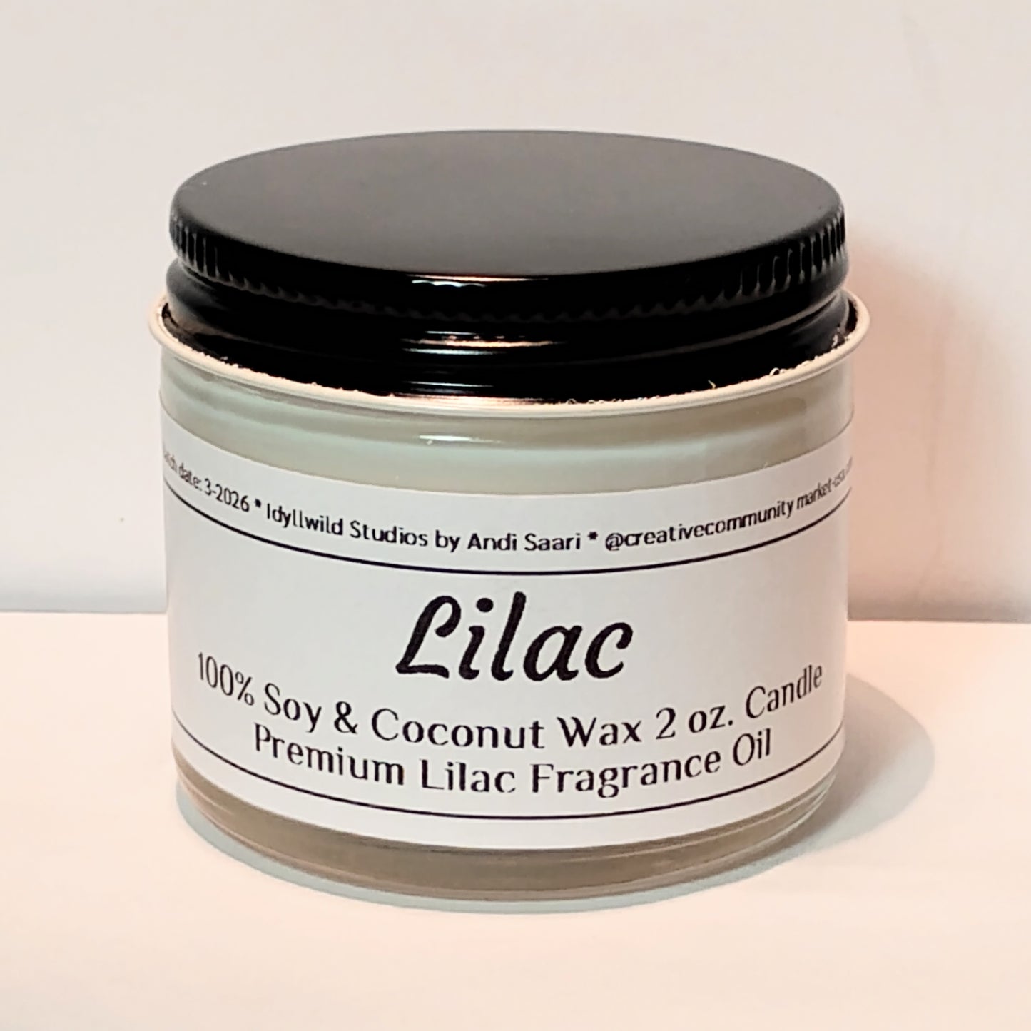 Candle jar labeled 'Lilac' with black lid on a light background